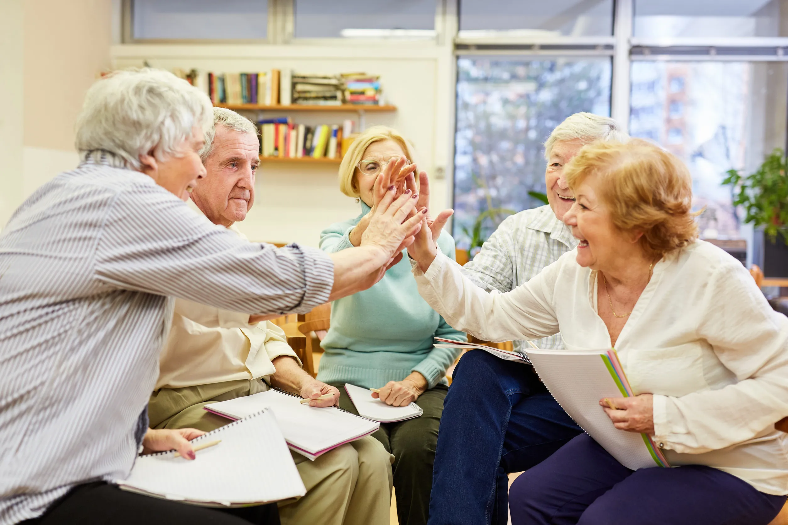 Seniors do high five in group therapy for motivation and community
